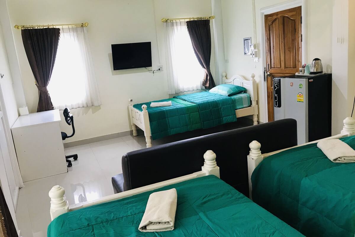 Habitación de hotel con dos camas, televisión, refrigerador y puerta de madera.