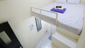 Een stapelbed met een matras, kussens en een klein elektronisch apparaat erop.