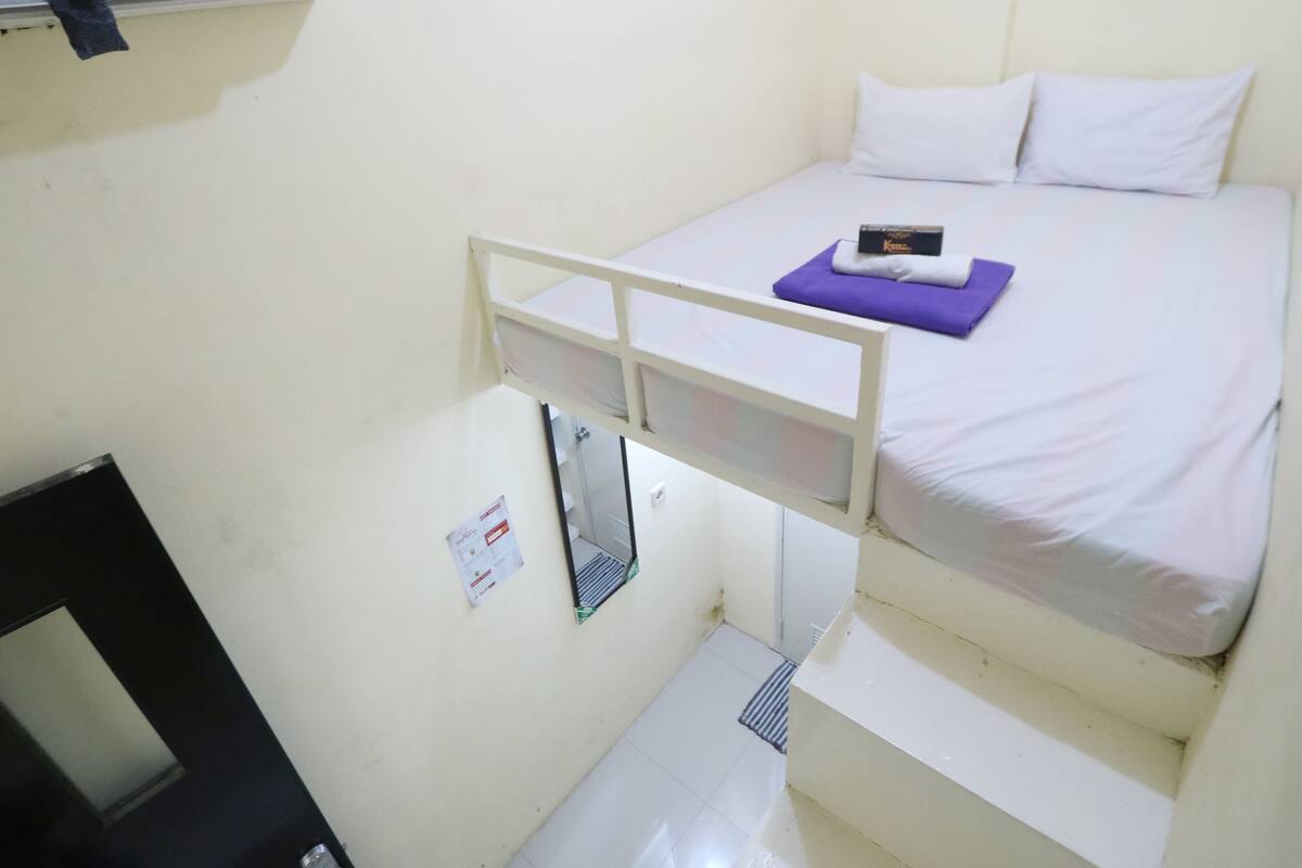 Een stapelbed met een matras, kussens en een klein elektronisch apparaat erop.