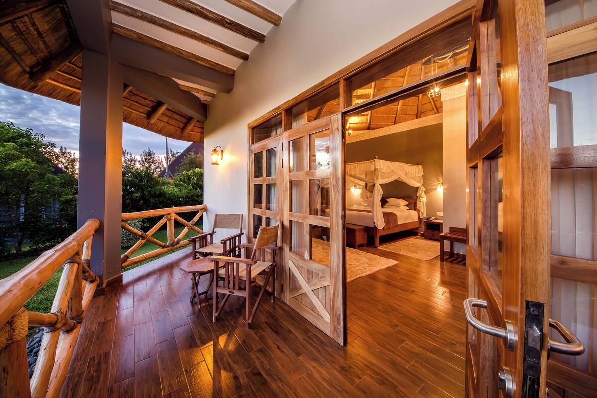 An open wooden door leading to a bedroom with a bed and a nightstand.