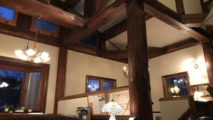 Quarto com vigas de madeira aparentes, um candelabro e uma mesa com abajur.