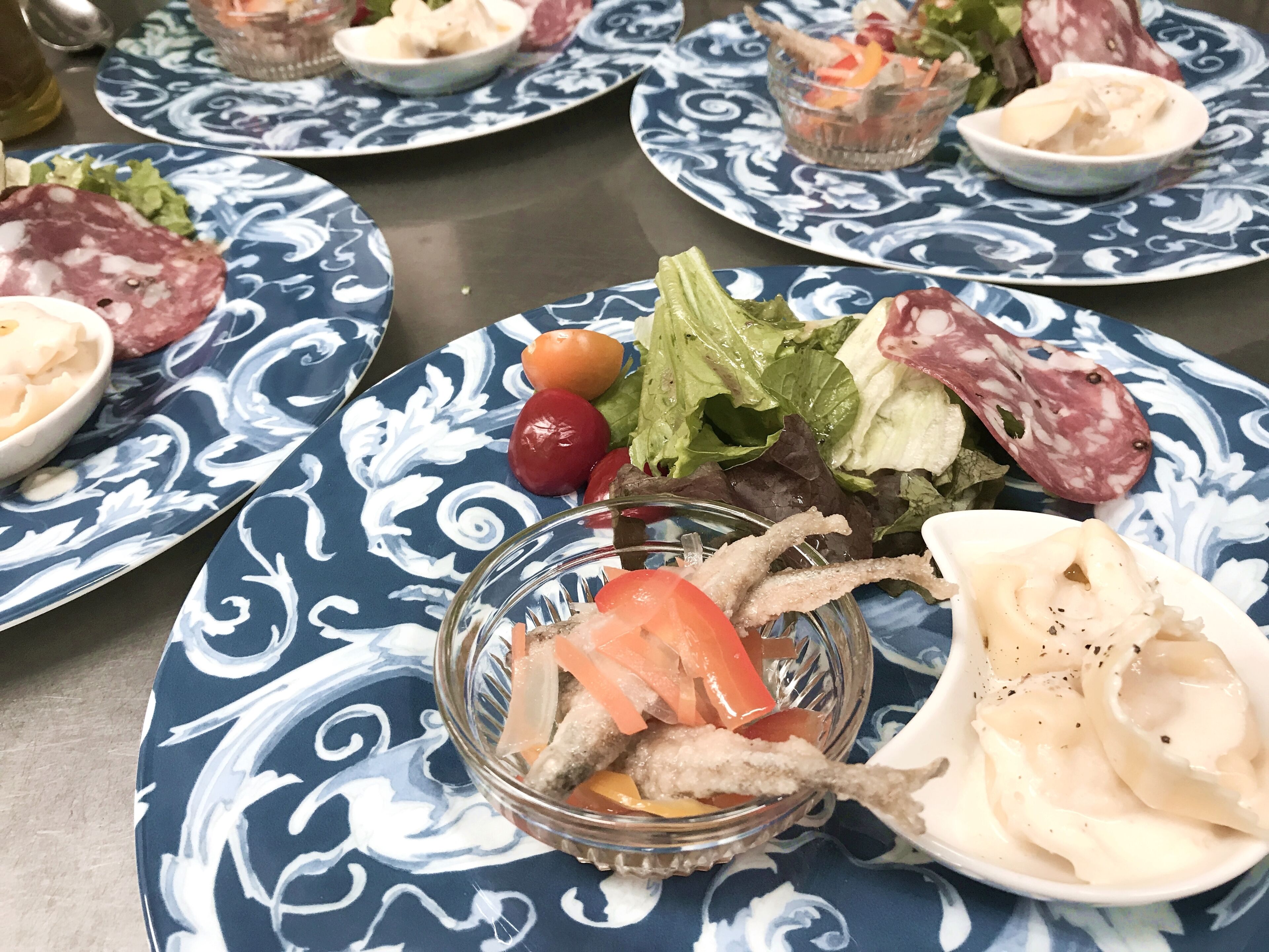 A table with plates of food, including various meats, vegetables, and a bowl of fish.