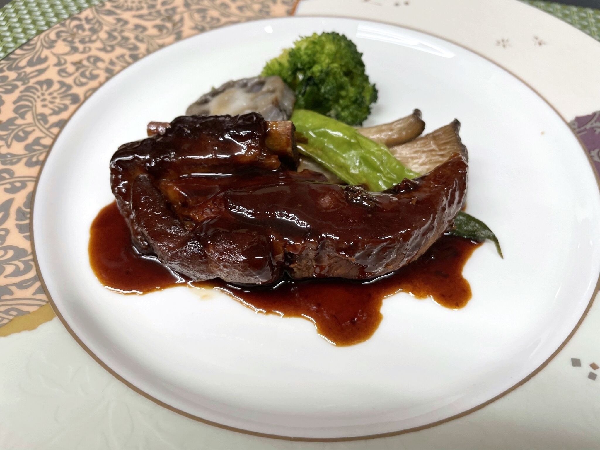 A plate with a piece of meat, broccoli, and mushrooms.