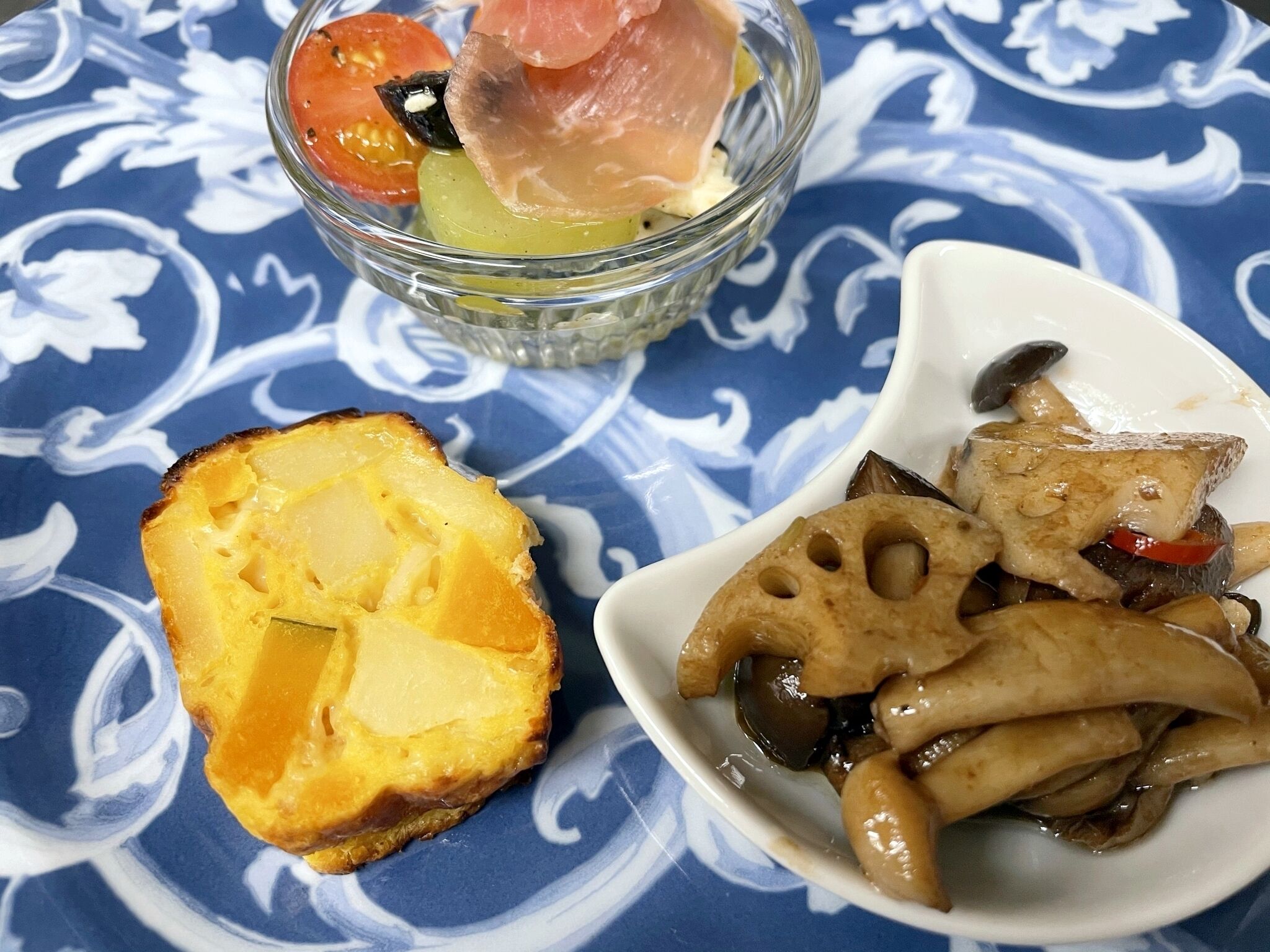 A plate with a slice of bread, a bowl of salad, and a dish of mushrooms.