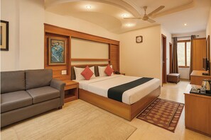 Una habitación de hotel con cama, sofá, escritorio y ventilador de techo.