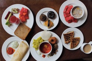 Una tavola imbandita con diverse pietanze per la colazione, tra cui pane tostato, croissant, waffle e una tazza di caffè.