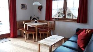 Un salon chaleureux avec une table à manger en bois, des rideaux rouges et un canapé bleu.