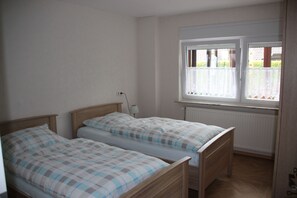 A bedroom with two single beds, a window with a view, and a radiator.