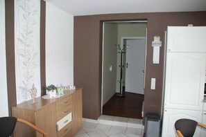 A hotel room with a wooden dresser, a chair, a desk, and a white door.