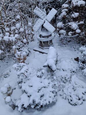 A snow-covered outdoor area with a windmill and a sheep statue.