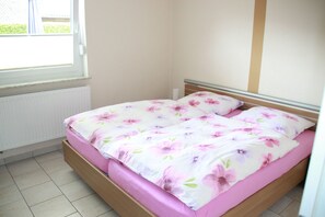 A bedroom with a bed, a window, and a radiator. - FeWo - Apartment Drieling, 85091 (Ostrhauderfehn)