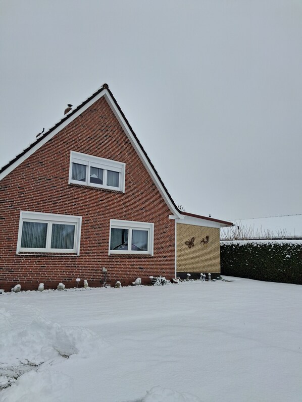 A red brick house with two windows and a small attached garage.