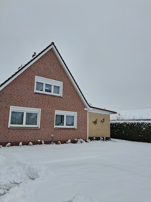 A red brick house with two windows and a small attached garage. - FeWo - Apartment Drieling, 85091 (Ostrhauderfehn)