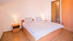 Een slaapkamer met een bed, nachtkastjes, een kledingkast en een deur naar een badkamer.
