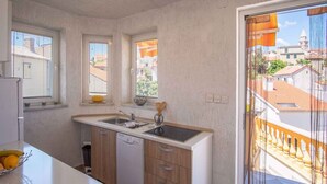 Een praktische keuken met een vaatwasser, een spoelbak en een raam met uitzicht op een woonwijk.