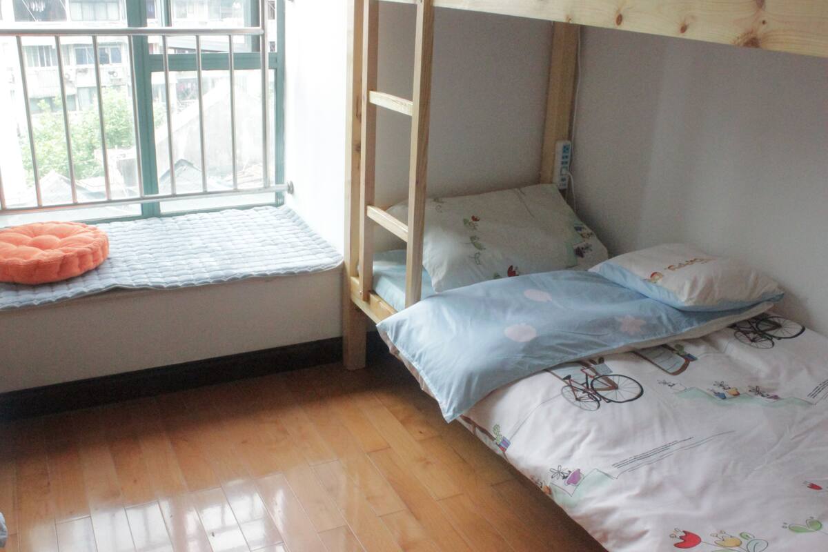 Una litera con un asiento junto a la ventana y un pequeño cojín naranja.