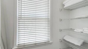 Une salle de bain avec une fenêtre, un porte-serviettes et une étagère où sont pliés les serviettes.