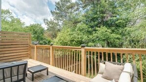 Une terrasse en bois avec un canapé et une table, entourée d’arbres.