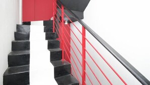 A staircase with black steps and a red handrail.