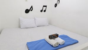 A neatly made bed with a blue blanket, white pillows, and a box of toiletries.