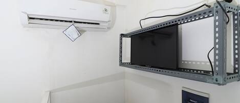 Una habitación con aire acondicionado instalado, una estantería de metal y una puerta numerada.