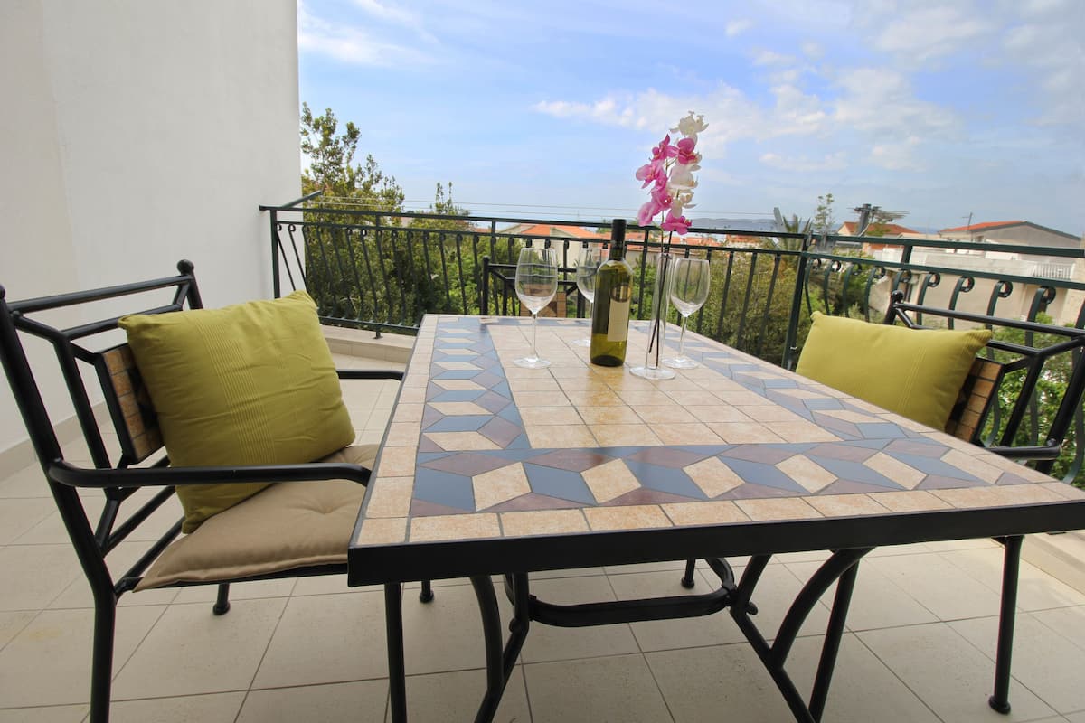 A balcony with a table and chairs, a bottle of wine, and a glass.