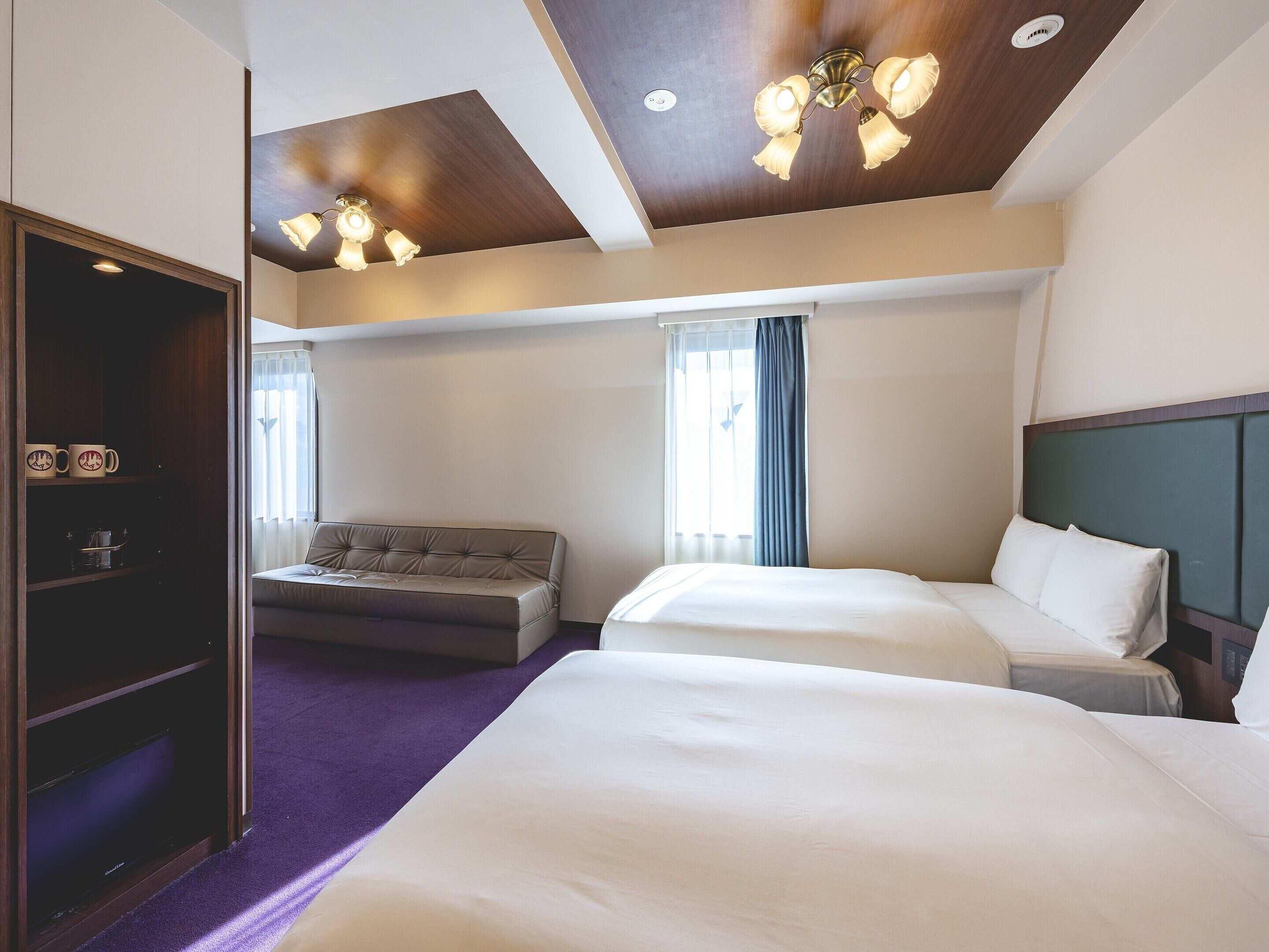 Habitación de hotel con una cama grande, un sofá, un armario y un techo con iluminación empotrada.