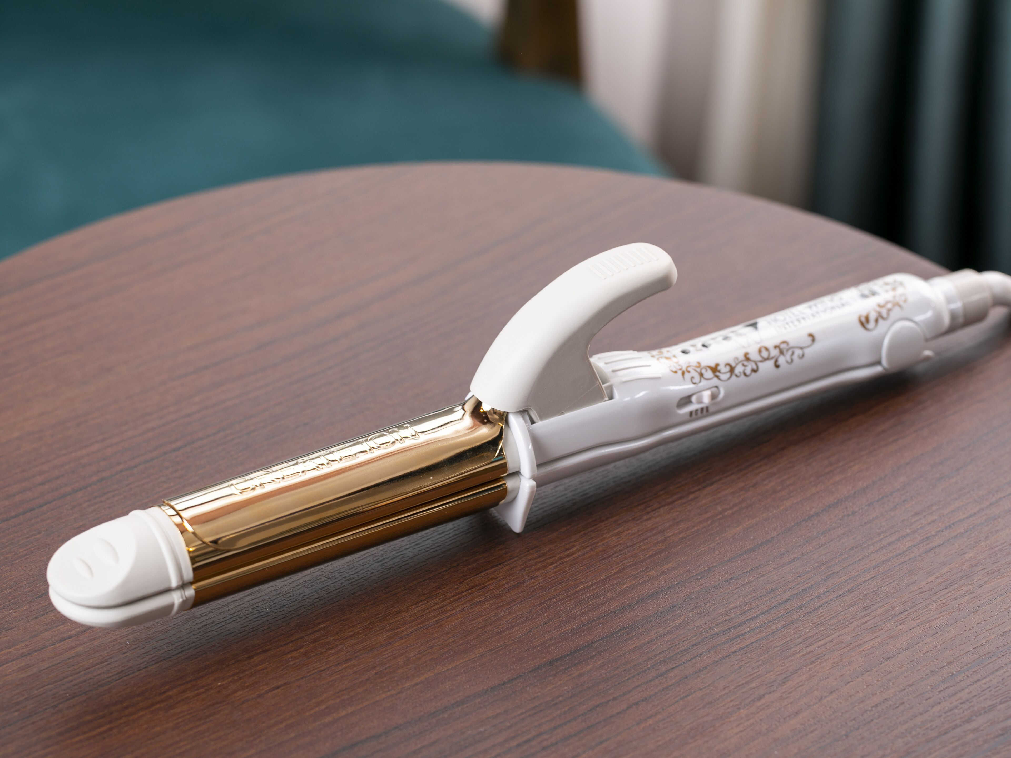 A white and gold hair straightener on a wooden surface.