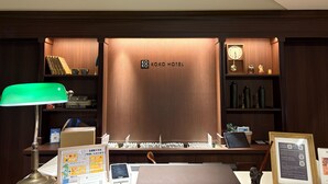 A reception desk with a clock, a framed menu, and a sign indicating the Koko Hotel. - KOKO HOTEL Ikebukuro (Tokyo)