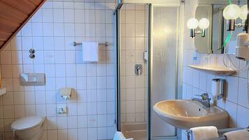Ein modernes Badezimmer mit einer einteiligen Duschkabine, einer weißen Toilette, einem Waschbecken mit Spiegel und einem Handtuchhalter.