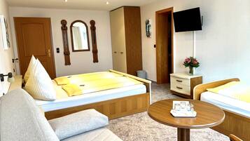 A hotel room with a bed, a sofa, a small table, a TV, and a wardrobe.