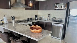A modern kitchen with dark cabinets, stainless steel appliances, and a granite countertop. - ☼Hypnotizing sea view on 17th floor ~Prime location in town ~Family getaway (Puerto Vallarta)