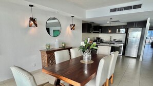 A modern dining area with a wooden table and chairs, a decorative vase, and a kitchen in the background. - ☼Hypnotizing sea view on 17th floor ~Prime location in town ~Family getaway (Puerto Vallarta)