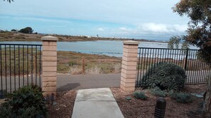 A gated entrance leading to a body of water with a view of a distant cityscape.