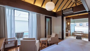Een hotelkamer met balkon, een bed, bureau, stoel en een klein tafeltje.