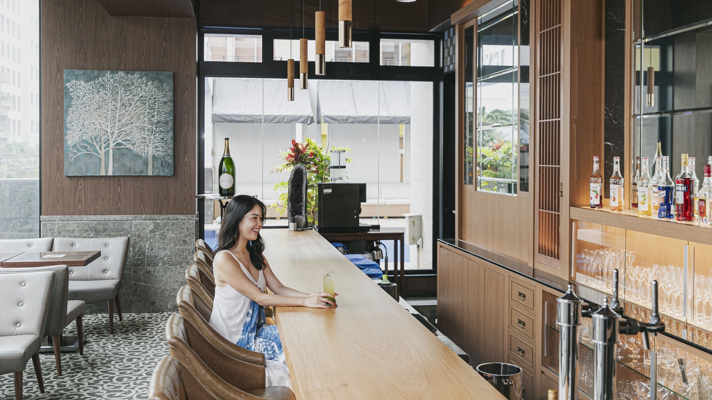 A bar area with a wooden counter, seating, and a wine display.