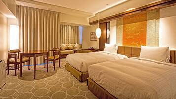 A hotel room with two beds, a desk, a chair, and a sofa.