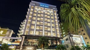 Een meerlaags hotel met een opvallend 'EXES'-bord bovenop.