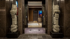 Una entrada con suelo de mármol, un tapete decorativo y dos estatuas de leones de piedra.
