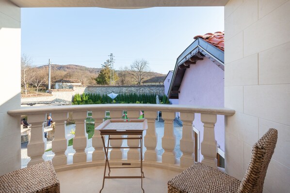 A balcony with a view of a traditional building and a stone wall. - Villa Ciconia (Veliko Tarnovo)