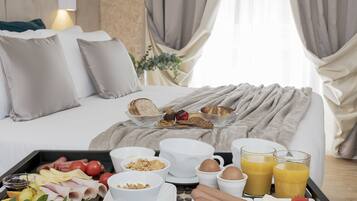 Een keurig opgemaakt ontbijtplateau met diverse etenswaren en drankjes, geplaatst op een bed in een hotelkamer.