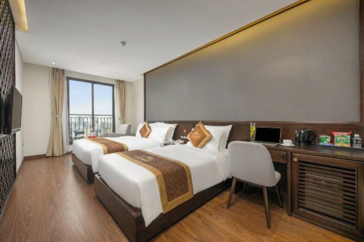Quarto de hotel com duas camas, uma escrivaninha e uma janela grande.
