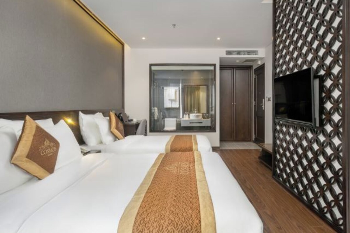 Habitación de hotel con dos camas, televisor y un ventanal grande.