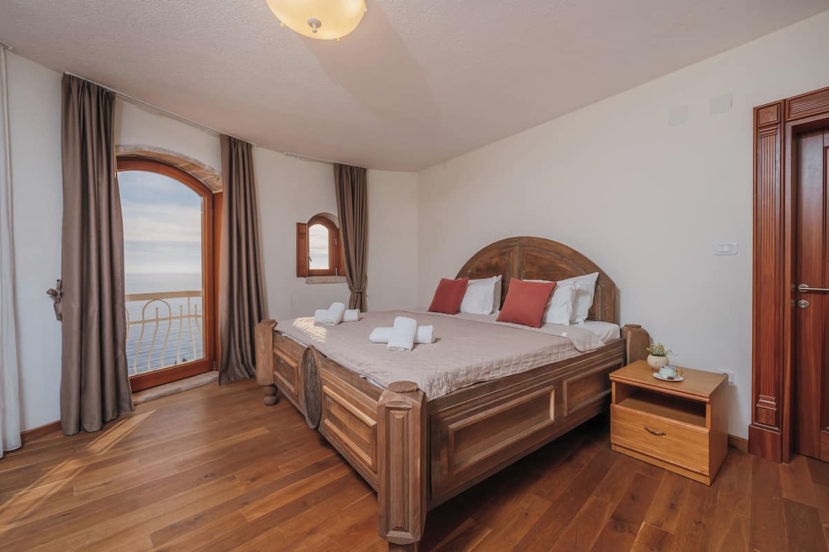 A bedroom with a wooden bed, a nightstand, a mirror, and a view through a door.