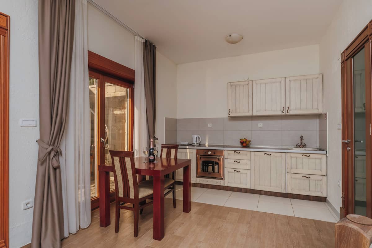A kitchen with wooden cabinets, a dining table with chairs, and a window with curtains.
