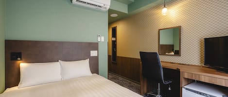 A hotel room with a bed, desk, chair, TV, and air conditioning unit.