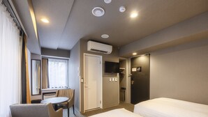 A hotel room with two beds, a desk, a chair, a TV, and an air conditioning unit. - KOKO HOTEL Shimbashi Onarimon (Tokyo)