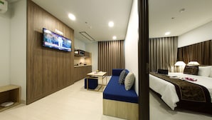 Une chambre d’hôtel moderne équipée d’une télévision, d’un canapé, d’un lit, d’un bureau et d’un coin cuisine.