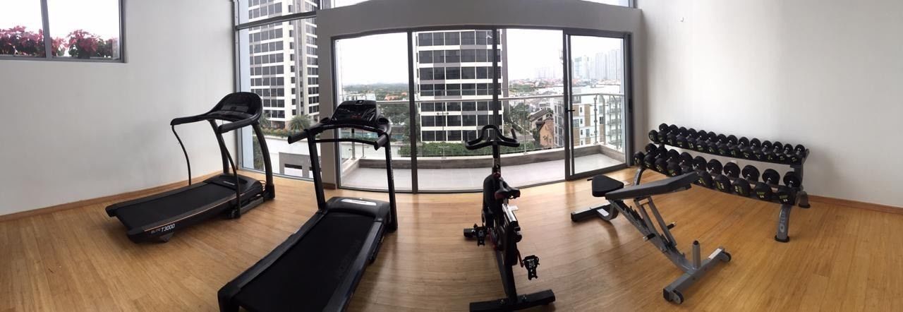 Un gimnasio con cintas de correr, una bicicleta estática y una prensa de pesas.