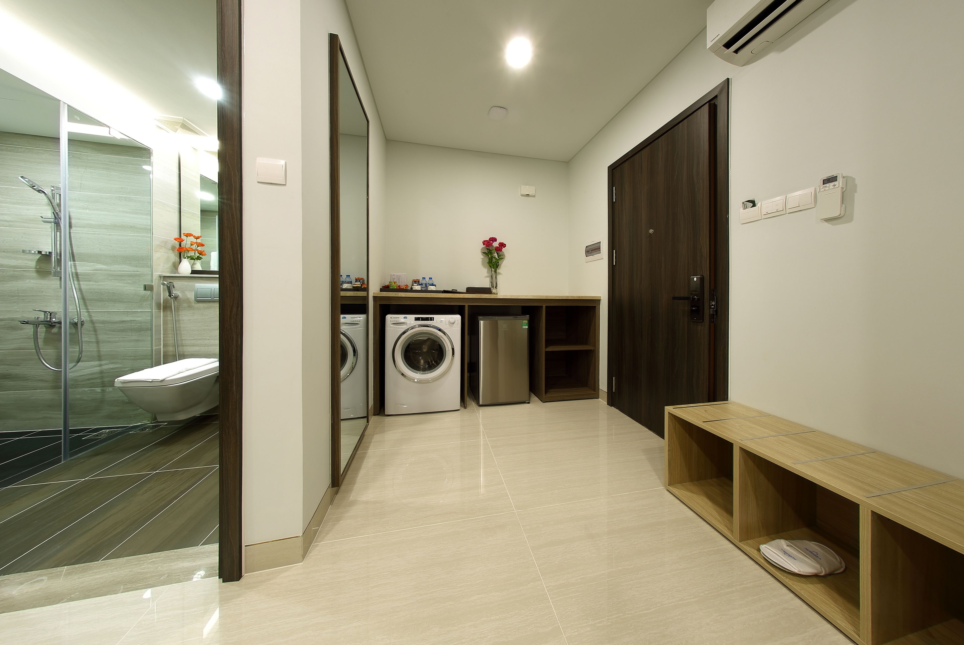 Une salle de bain moderne équipée d’une douche, de toilettes, d’un lave-linge et d’un banc.